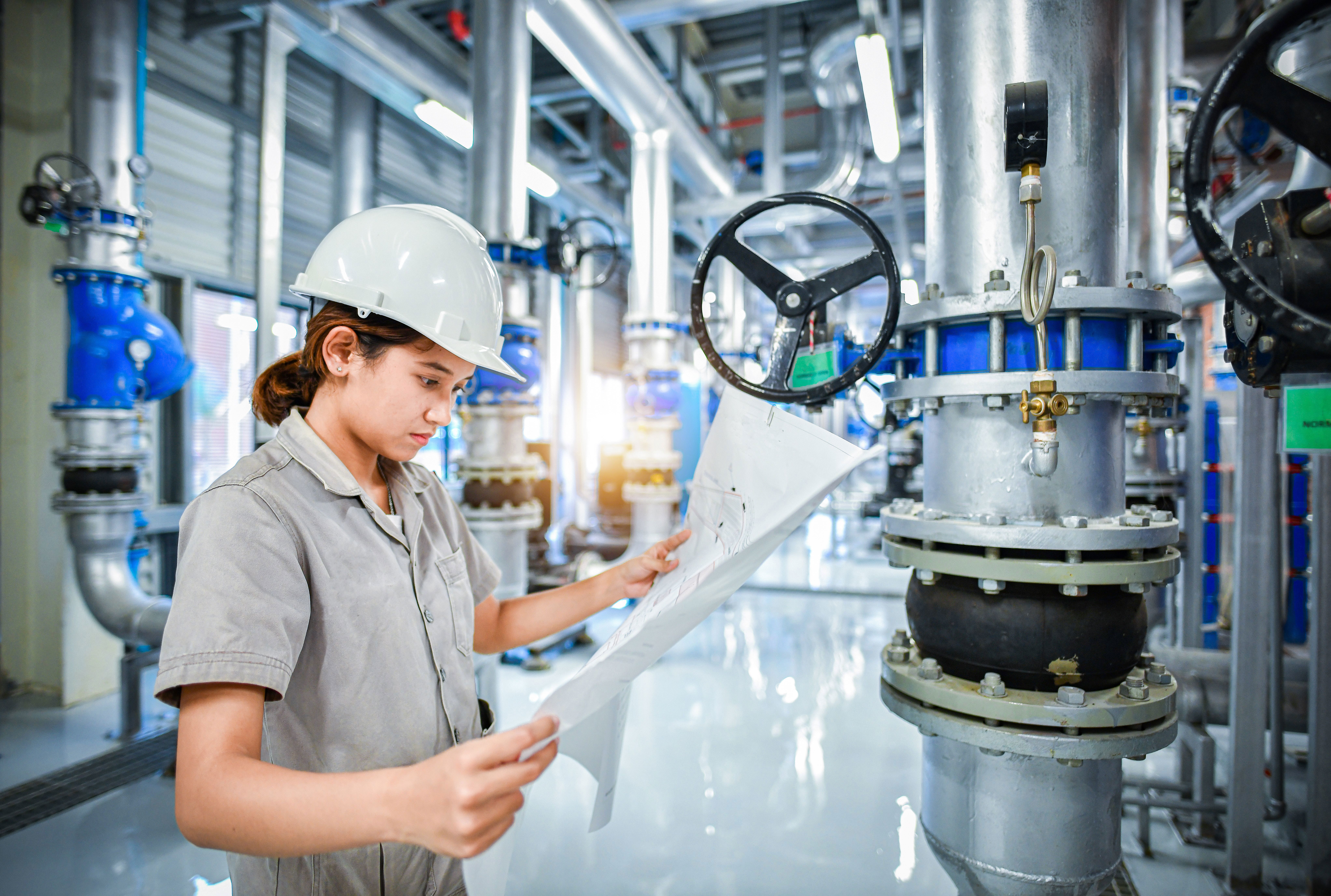 Engineer in Compressor Room wearing a hard hat and looking at a document